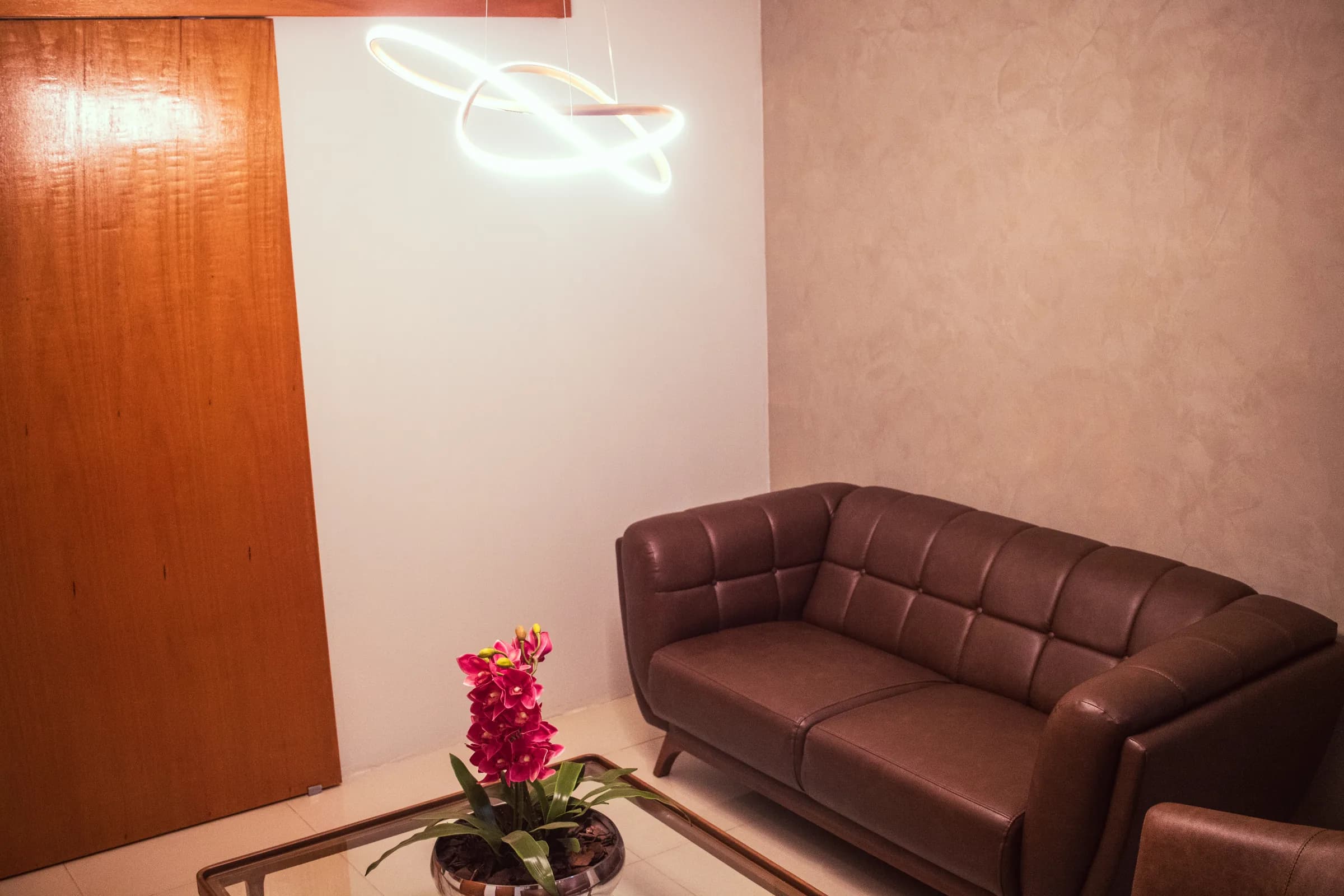 Recepção da clínica com sofá de couro e iluminação suave
